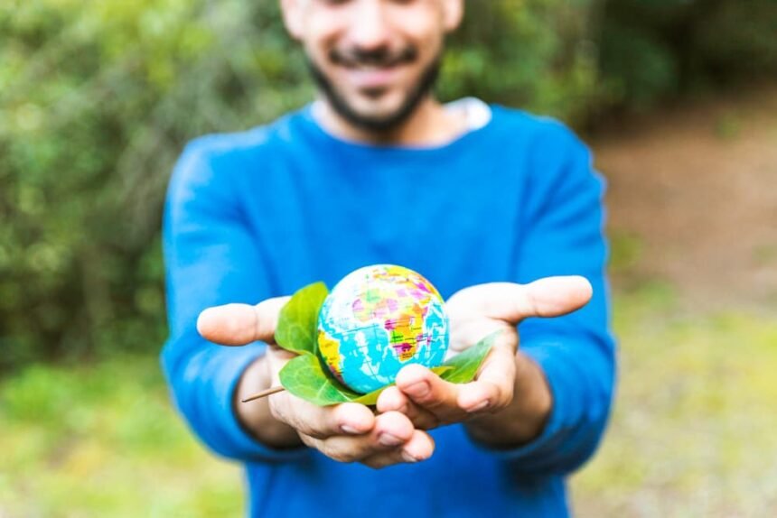 Activista sosteniendo un globo y una hoja verde sonriendo.