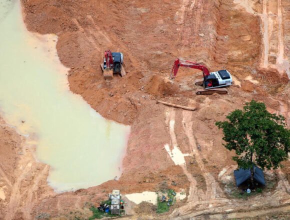 Multa histórica a minera en Maipú por operar sin permiso ambiental Vista aérea de maquinaria pesada excavando en un terreno erosionado con charcos de agua y ausencia de cobertura vegetal, representando una operación minera irregular.