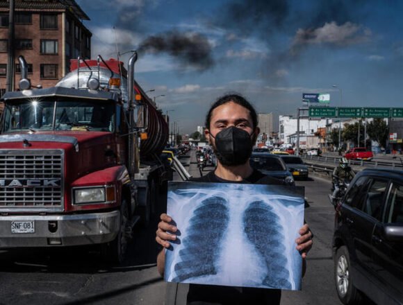 Respirar no debería enfermar Hombre con barbijo sostiene una radiografía de pulmones frente a una calle con tráfico pesado y humo negro saliendo de un camión, simbolizando la contaminación del aire.