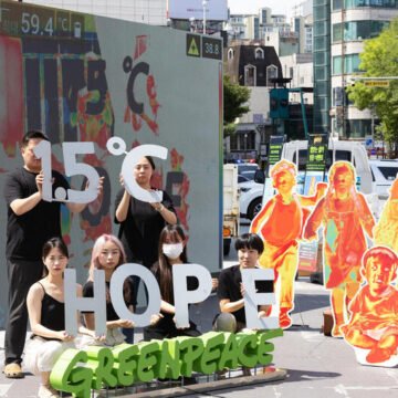 Activistas de Greenpeace realizan una intervención urbana con carteles sobre el calentamiento global y una meta climática de 1.5 °C.