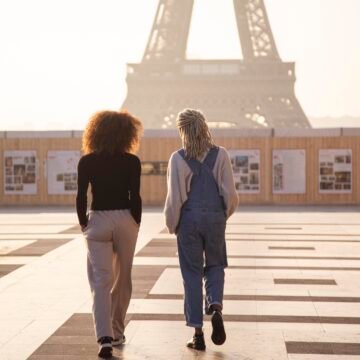 Caminata vespertina en París frente a la Torre Eiffel Dos personas caminando al atardecer frente a la Torre Eiffel